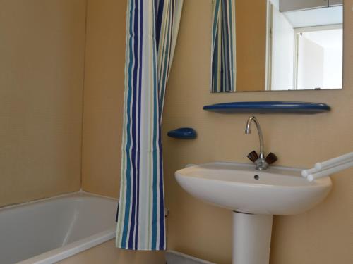 uma casa de banho com um lavatório, um espelho e uma banheira em Appartement Saint-Cyprien, 2 pièces, 6 personnes - FR-1-225D-25 em Saint-Cyprien-Plage