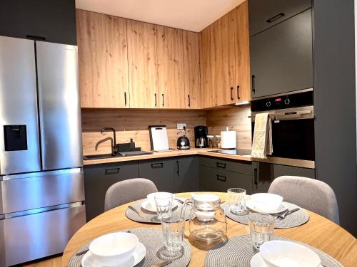 a kitchen with a table with plates and glasses on it at Apartament 25 Rowery, Spacery w Dolinie Baryczy - 5D Apartamenty in Milicz