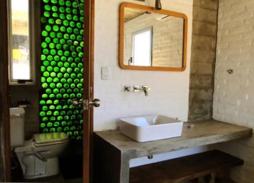 a bathroom with a sink and a mirror and a toilet at Miralejos in Punta Del Diablo