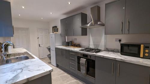una cocina con electrodomésticos de acero inoxidable y armarios grises en Huge Weekly & Monthly Savings - Free Parking - Wi-Fi & Netflix, en Wolverhampton