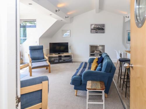 a living room with a blue couch and two chairs at The Penthouse in Lyme Regis
