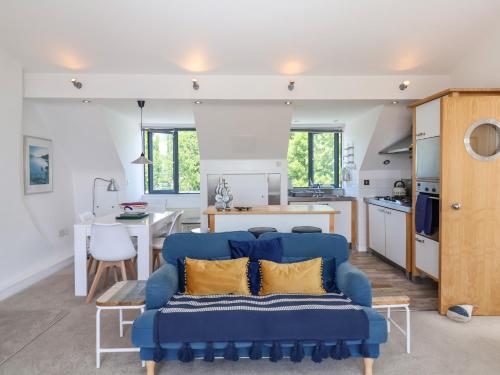a living room with a blue couch and a kitchen at The Penthouse in Lyme Regis