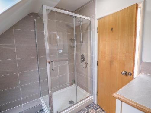 een douche met een glazen deur in een badkamer bij The Penthouse in Lyme Regis