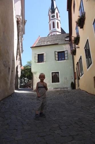 a young boy standing in an alley in front of a building at UNESCO 14 century in Český Krumlov