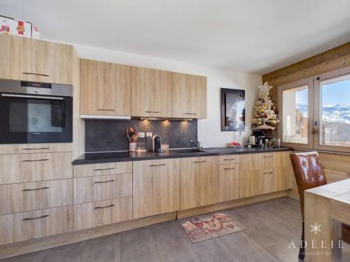 une cuisine avec des placards en bois et une grande fenêtre dans l'établissement Charmant 3 pièces aux pieds des pistes avec balcon, parking et WiFi - FR-1-398-606, à Montvalezan
