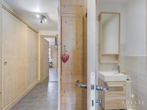 La salle de bains est pourvue d'une porte en bois et d'un lavabo. dans l'établissement Charmant 3 pièces aux pieds des pistes avec balcon, parking et WiFi - FR-1-398-606, à Montvalezan