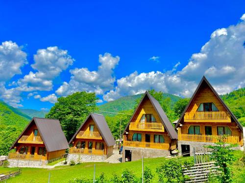 a row of wooden homes in a green mountain at Villa Dardania in Peje
