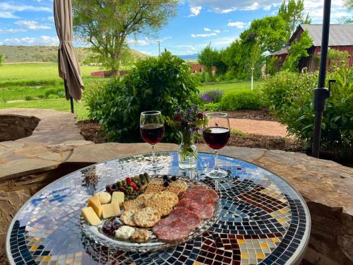 a plate of food and two glasses of wine at Cosmo Glamping Tent at Zenzen Gardens in Paonia