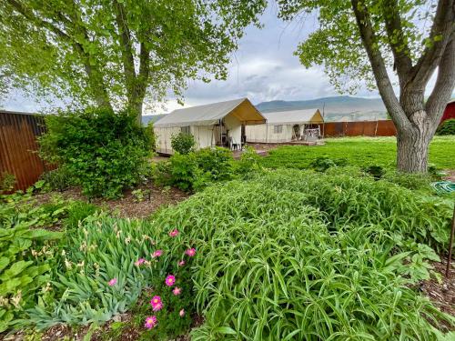 a garden with flowers and trees and houses at Cosmo Glamping Tent at Zenzen Gardens in Paonia