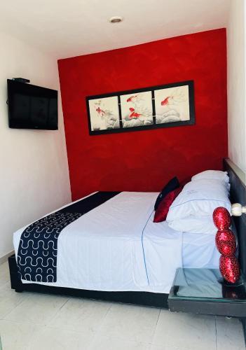 a bedroom with a bed with a red wall at Quinta Santa Anita in Playa del Carmen