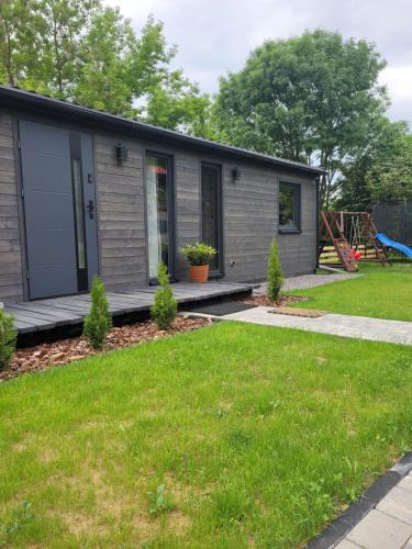 a tiny house in a yard with a playground at DomEK Obok Rzeki in Bałtów