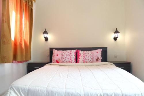 a bedroom with a white bed with pink pillows at Dar tabazariste in Marrakesh