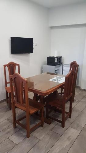 drewniany stół z 4 krzesłami i telewizor w obiekcie Apart B w mieście San Luis