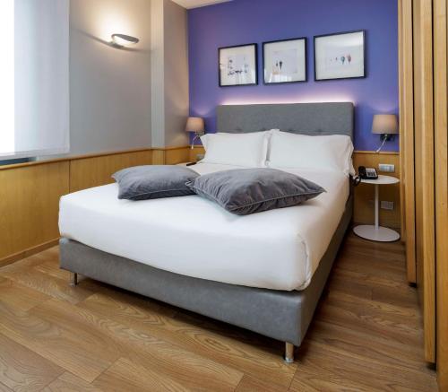 トリノにあるベスト ウェスタン エグゼクティブ ホテル アンド スイーツの紫の壁のベッドルーム1室(白い大型ベッド1台付)