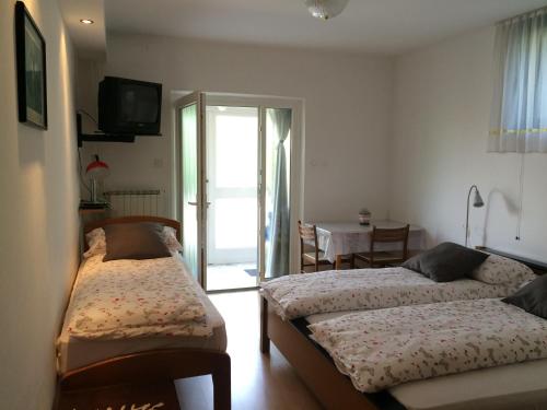 a room with two beds and a table and a television at Tourist Rooms Sajovic in Postojna