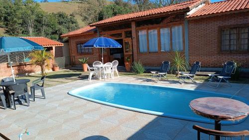 uma piscina com mesa e cadeiras e uma casa em Pousada Estrelícia em Cunha