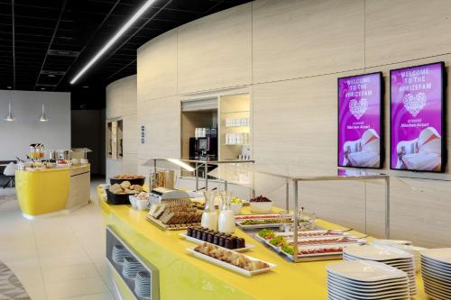 a buffet of food on a yellow counter in a store at Prize by Radisson, Munich Airport in Hallbergmoos
