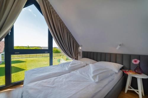 ein Bett in einem Schlafzimmer mit einem großen Fenster in der Unterkunft Kaszubia in Jastrzębia Góra