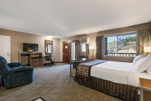 ein Hotelzimmer mit einem großen Bett und einem Schreibtisch in der Unterkunft Heritage Inn - Yosemite/Sonora in Sonora
