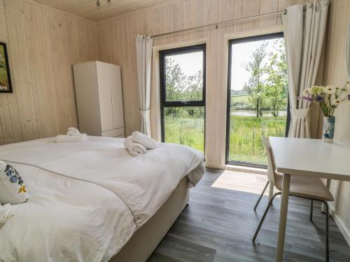 a bedroom with a bed and a desk and a window at Dragonfly Lodge in Bideford