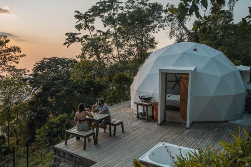 two people sitting on benches in front of a tent at Terramia Estate in Minca