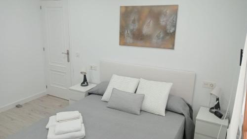 een witte slaapkamer met een bed met 2 kussens bij Apartamento a estrenar a 300 m de la playa de San Lorenzo en Gijón in Gijón