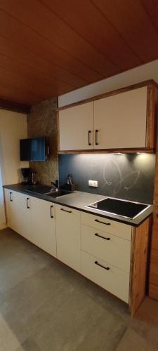 een keuken met witte kasten en een zwart aanrecht bij Innerraderhof in Prato alla Drava