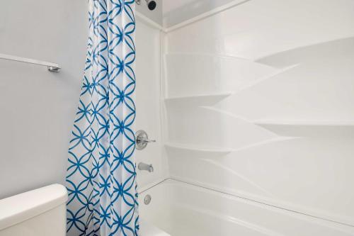 uma casa de banho com um chuveiro com uma cortina de chuveiro azul e branca em Atlantic Beach Escape about 2 Mi to Barefoot Landing! em Myrtle Beach