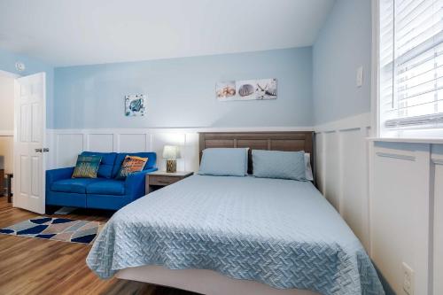 a bedroom with a bed and a blue couch at 2 Mi to Barefoot Landing! Baileys Beach Cottage in Myrtle Beach