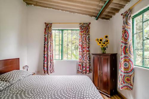 a bedroom with a bed and two windows at Finca Umnisa - Choachi in Choachí