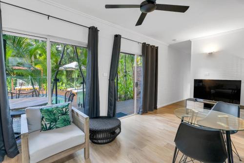 a living room with a ceiling fan and a table and chairs at The Palms At Palm Cove in Palm Cove
