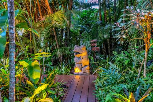 a wooden walkway in a tropical garden with a statue at The Palms At Palm Cove in Palm Cove