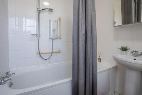 ein weißes Bad mit einer Dusche und einem Waschbecken in der Unterkunft Comfy 3Bed House-Parking-Garden in Newcastle upon Tyne