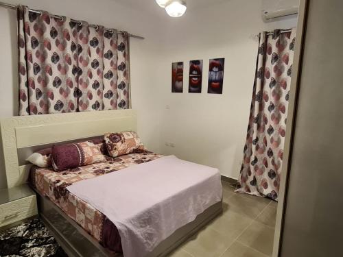 een kleine slaapkamer met een bed en een raam bij قريه امواج الساحل الشمالى in Abû Zeira