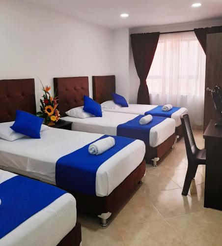 a hotel room with four beds with blue pillows at HOTEL RAI MEDELLIN in Medellín