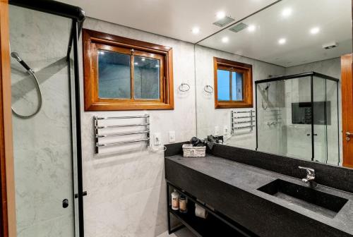 um banheiro com pia e box de vidro em Flat 5 estrelas em Campos do Jordão em Campos de Jordão