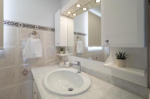 een witte badkamer met een wastafel en een spiegel bij Villa Kostamaria in Petrití