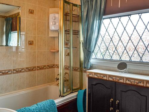 baño con bañera y ducha y ventana en Josies Den en Bridlington