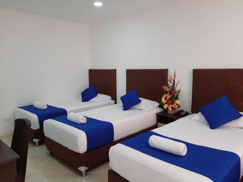 trzy łóżka w pokoju niebiesko-białym w obiekcie HOTEL RAI MEDELLIN w mieście Medellín