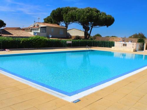 une grande piscine bleue dans une cour dans l'établissement Villa Mitoyenne avec Terrasse, Piscine et Parking à Proximité de la Plage et du Centre - FR-1-607-27, au Cap d'Agde