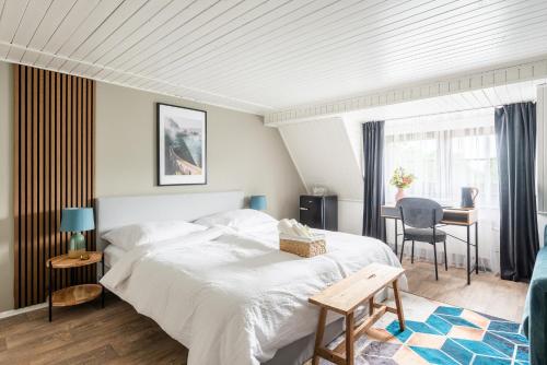 1 dormitorio con 1 cama blanca grande y escritorio en Penzion Mezi buky en Chřibská