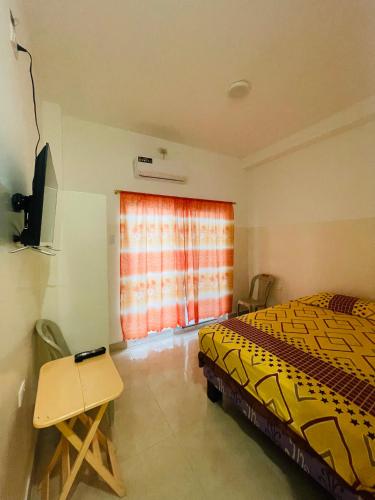a bedroom with a bed and a table and a window at Casa de Huéspedes Playas Arena in Playas