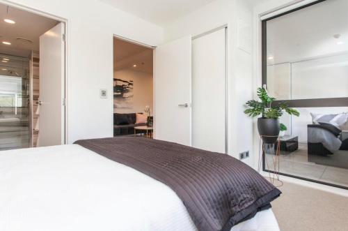 a bedroom with a white bed and a large window at Spacious one bedroom apartment in Newmarket in Auckland