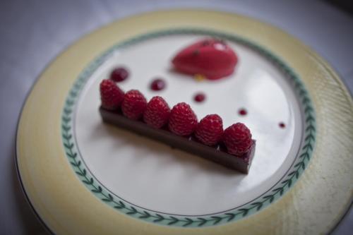 a white plate with a piece of cake and raspberries at Auberge du Raisin in Cully