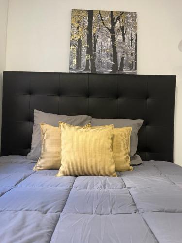 uma cama com uma cabeceira preta e duas almofadas amarelas em Perfect Studio Mouraria em Lisboa