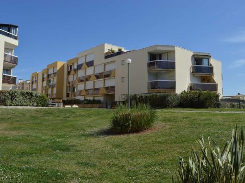 un bâtiment avec un champ herbeux devant lui dans l'établissement Studio climatisé 4 couchages proche plage et commerces au Grau-du-Roi - FR-1-250-160, au Grau-du-Roi