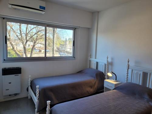 1 dormitorio con 2 camas y ventana en Departamento céntrico villa ramallo en Ramallo