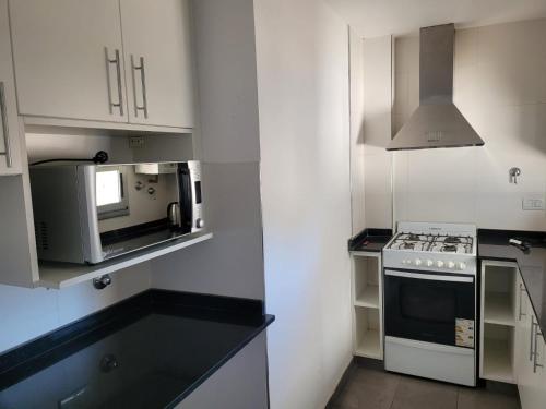 a white kitchen with a stove and a microwave at Departamento céntrico villa ramallo in Ramallo