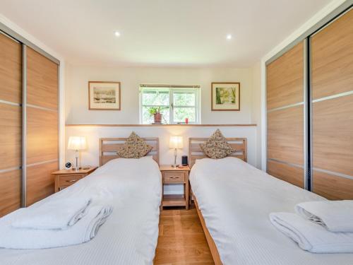 two beds in a room with wood paneling at Tan Y Castell Cottage in Lampeter-Velfrey