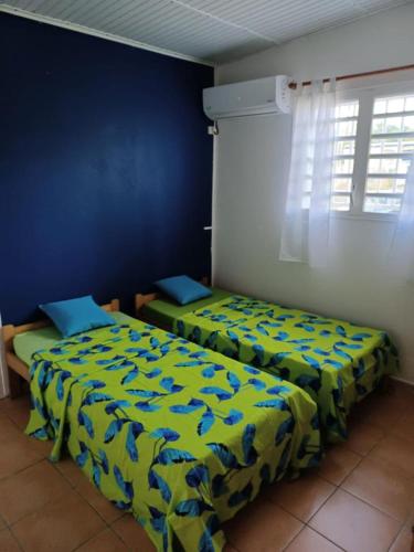 ein Schlafzimmer mit 2 Betten und einer blauen Wand in der Unterkunft Mancenillier in Petit-Canal